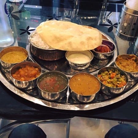 curries in metal bowls from crispy dosa with rice with a poppadom stacked on top