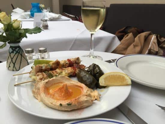 Picture of a meal from Jakobs on a white plate of lemon, hummus and kebabs