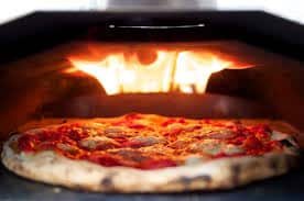 Picture of a pizza with bubbling cheese in a stone oven with burnt dough crust