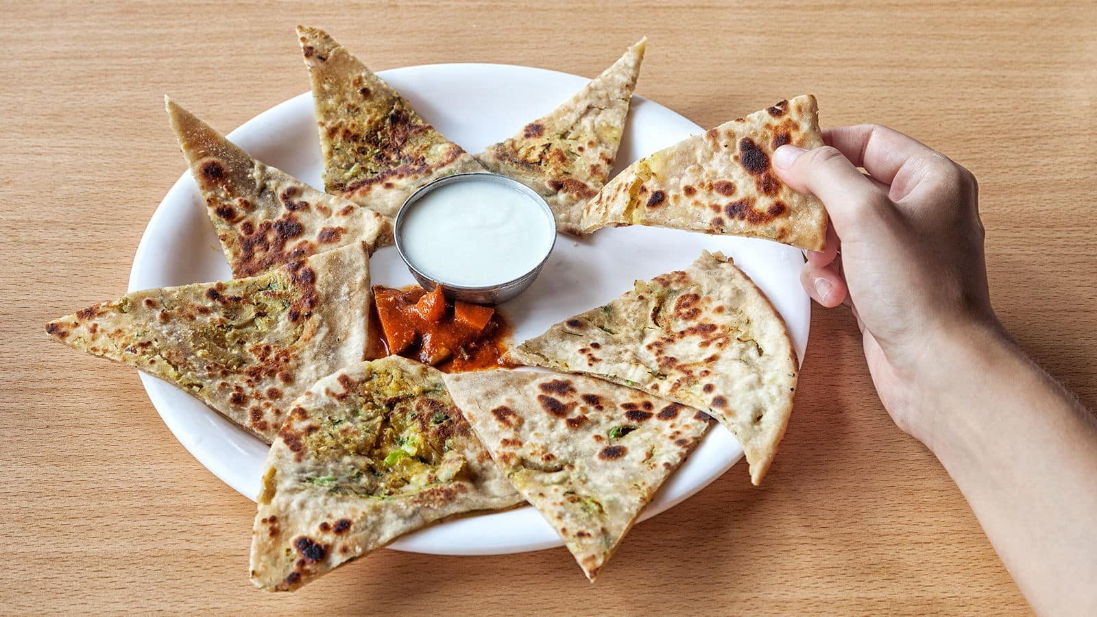 Picture of dosa or naan with dip on a plate on a table